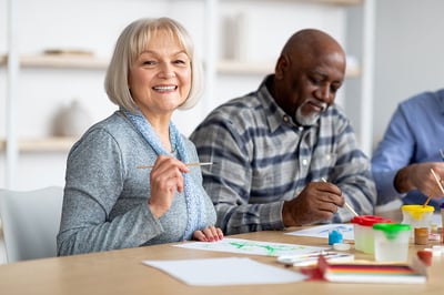 positive-senior-woman-enjoying-painting-with-brush