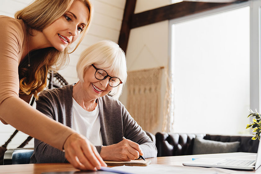 Insurance agent standing in front of laptop and giving advise to senior woman.